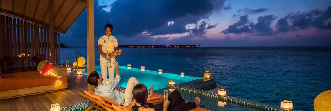 Club Med Villas de FInolhu, aux Maldives - Photo d'un couple sur des transat devant la piscine et l'océan Indien