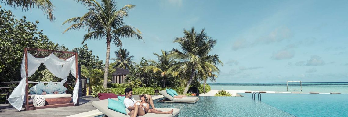 Club Med Villas de FInolhu, aux Maldives - Photo d'un couple sur un sofa sur la piscine à débordements devant la lagune