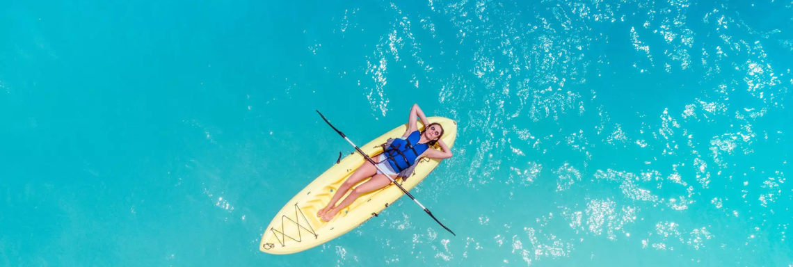 Club Med Columbus Isle, au Bahamas - Une femme est couchée sur un kayak, en pleine mer.