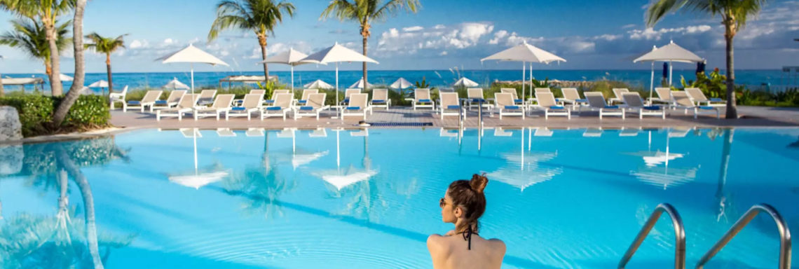 Club Med Columbus Isle, au Bahamas - Une femme est assise sur le bord de la piscine, du complexe, face à la mer