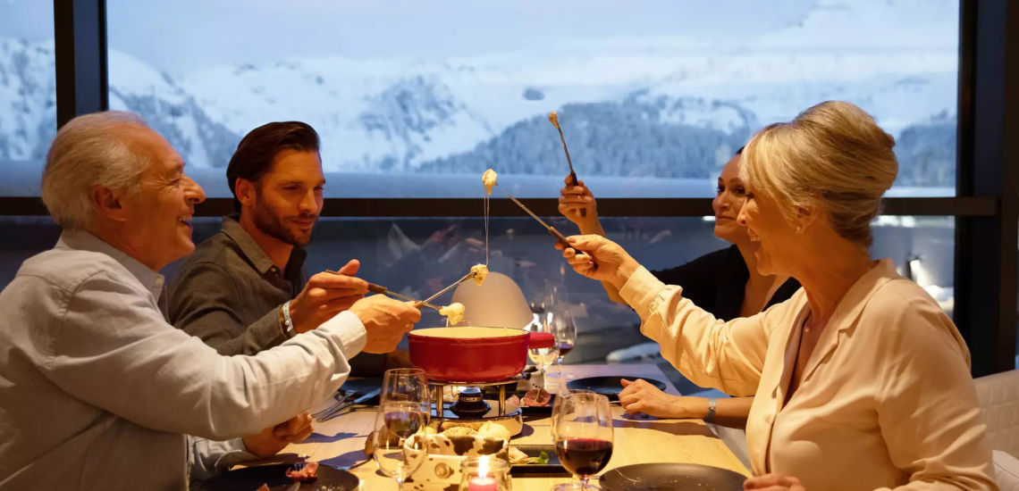 Club Med Tignes Val Claret, France - Image d'un groupe de personne qui mange une fondue avec vue sur la montagne en arrière plan